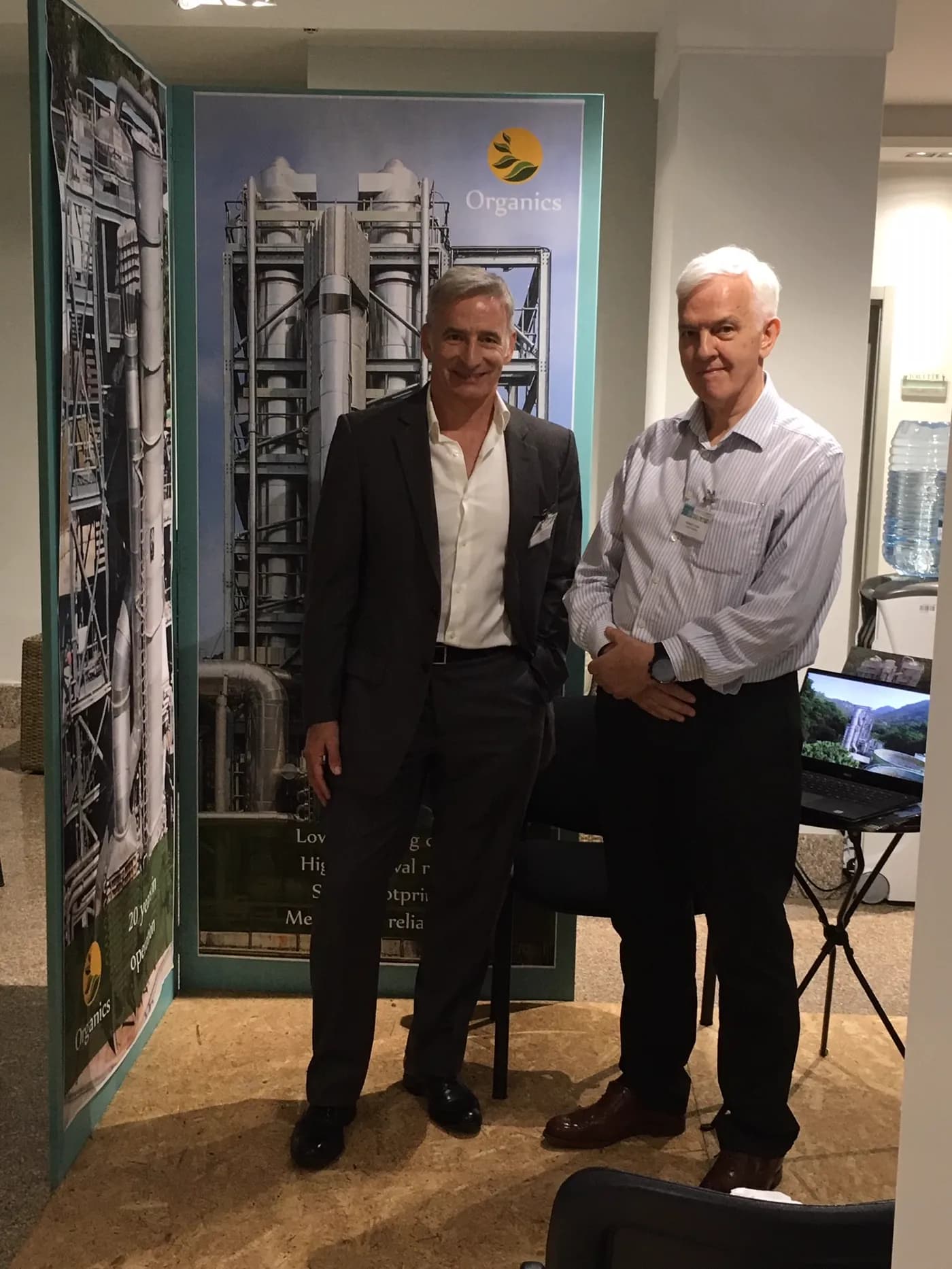 Two Organics representatives in front of a stripping plant display at a conference